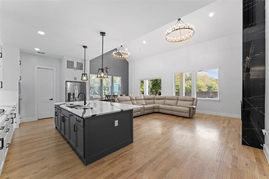 Kitchen featuring white cabinets, glass insert cabinets, pendant lighting, a center island with sink, and recessed lighting Kitchen featuring white cabinets, glass insert cabinets, pendant lighting, a center island with sink, and recessed lighting