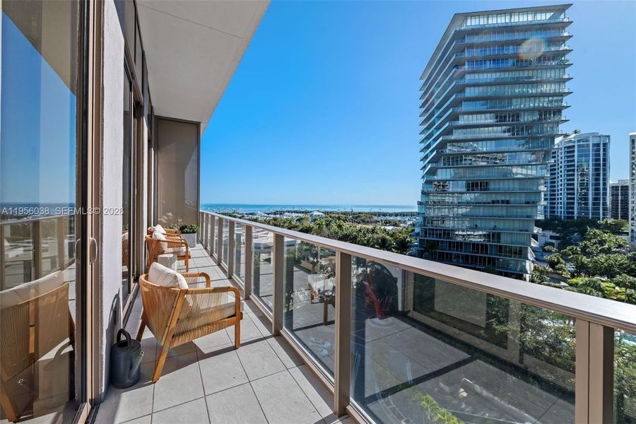 spacious private balcony with tranquil views of lush greenery, marina, and skyline—ideal for relaxing or entertaining