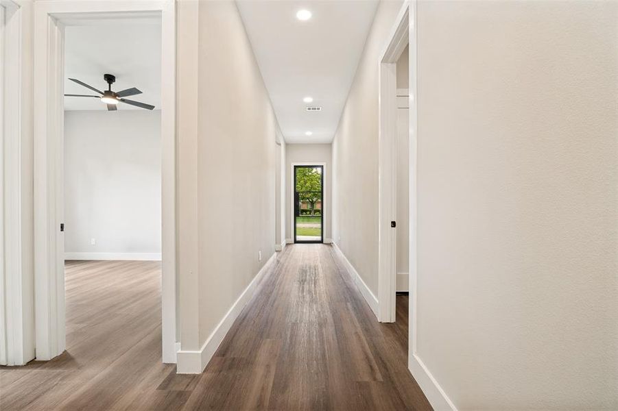 Long hallway featuring wood-finish flooring, recessed lighting, and a full-light glass panel door providing exterior visibility