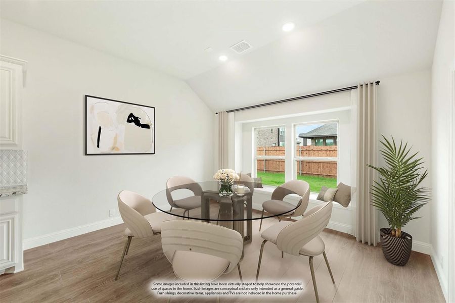 Dining area with round glass table, beige chairs, vaulted ceiling, and large window overlooking backyard Dining area with round glass table, beige chairs, vaulted ceiling, and large window overlooking backyard