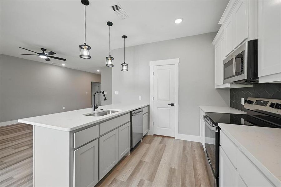 Kitchen with stainless steel appliances, a sink, a peninsula, light wood finished floors, and recessed lighting