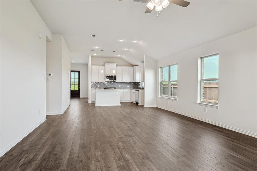 Unfurnished living room featuring ceiling fan, vaulted ceiling, sink, and dark hardwood / wood-style flooring