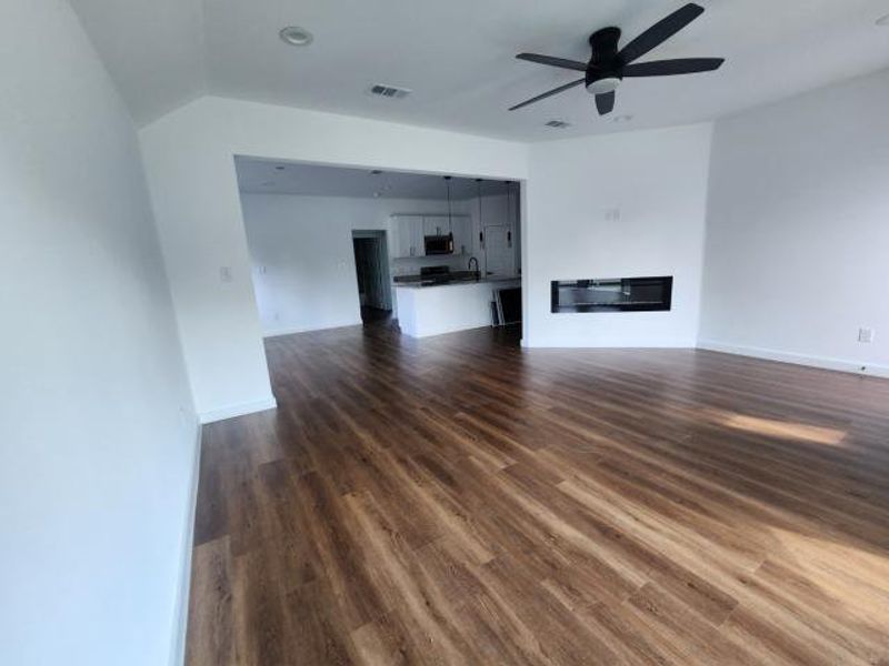 Unfurnished living room featuring dark wood-type flooring and a ceiling fan Unfurnished living room featuring dark wood-type flooring and a ceiling fan