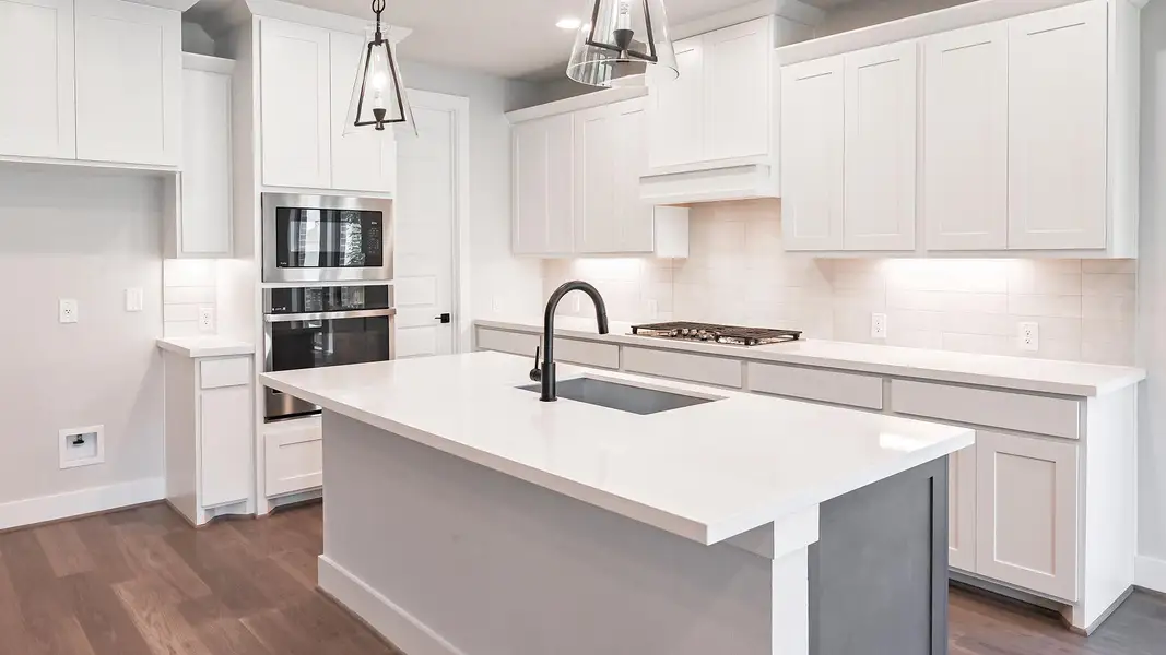 Kitchen with dark wood-type flooring, appliances with stainless steel finishes, tasteful backsplash, white cabinetry, and recessed lighting