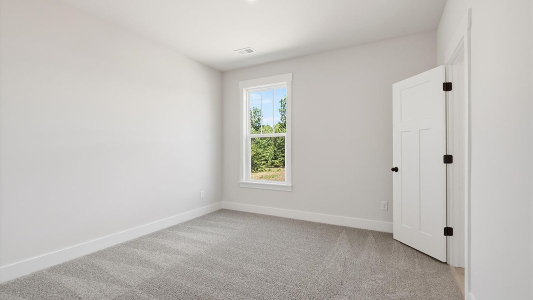 Bright and serene bedroom with comfortable carpeted flooring and large windows for vibrant light by DRB Homes