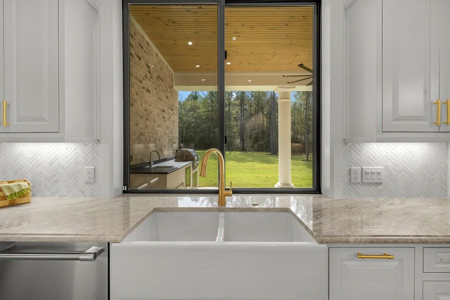 Farmhouse-style sink with a view through the window of the patio and outdoor kitchen, combining functionality with a scenic backdrop Farmhouse-style sink with a view through the window of the patio and outdoor kitchen, combining functionality with a scenic backdrop