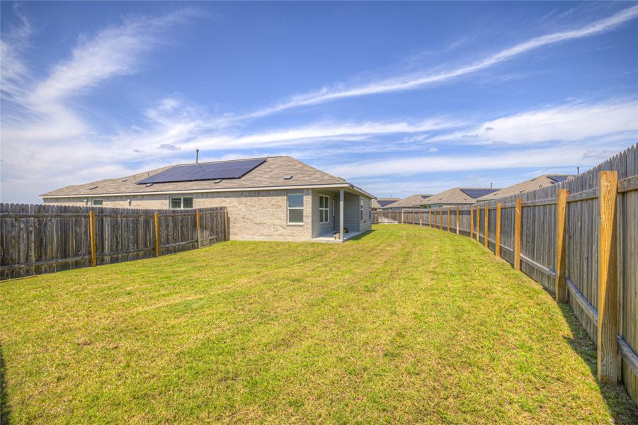 A spacious backyard with vibrant green lawn, enclosed by a sturdy privacy fence.