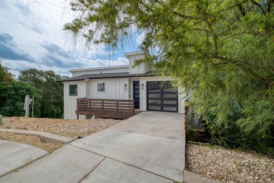 A modern facade with a sleek garage door and inviting front porch complements the natural, sloping landscape. A modern facade with a sleek garage door and inviting front porch complements the natural, sloping landscape.