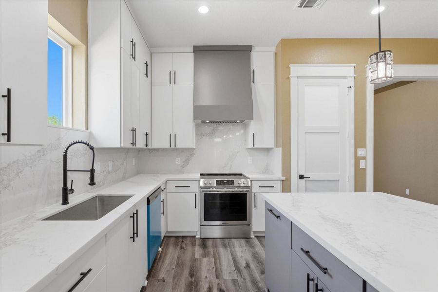 The kitchen offers a stylish frosted glass pantry door, a built-in trash bin within the island, and a convenient built-in microwave nook, an electric stainless steel stove and a dishwasher.