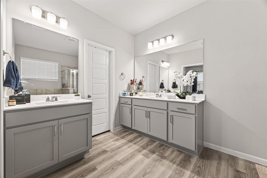 Dual vanities and chic lighting in the primary bath transform the daily routine into a luxury experience with plenty of elbow room.