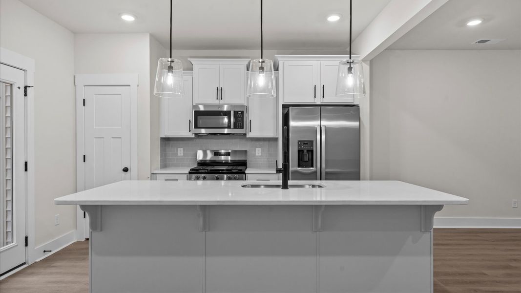 Tasteful design meets functional luxury in this kitchen with a 9-foot island and modern pendant lighting