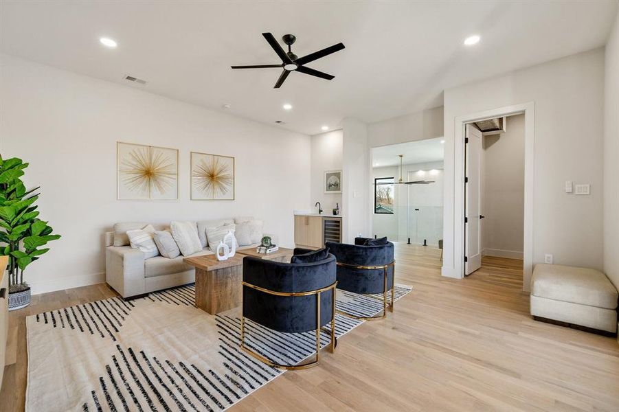 Living room with light hardwood / wood-style flooring, beverage cooler, and ceiling fan