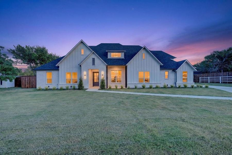 Contemporary farmhouse-style exterior featuring a dark asphalt shingle roof, white brick facade, and vertical board-and-batten siding Contemporary farmhouse-style exterior featuring a dark asphalt shingle roof, white brick facade, and vertical board-and-batten siding
