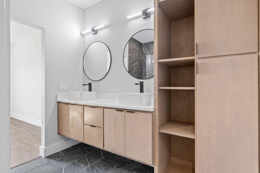 Bathroom featuring dark marble finish floors and double vanity