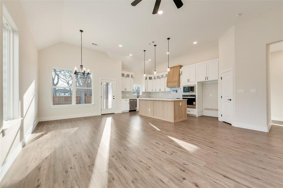 Kitchen featuring open floor plan, a chandelier, light countertops, light wood-style floors, and wall oven