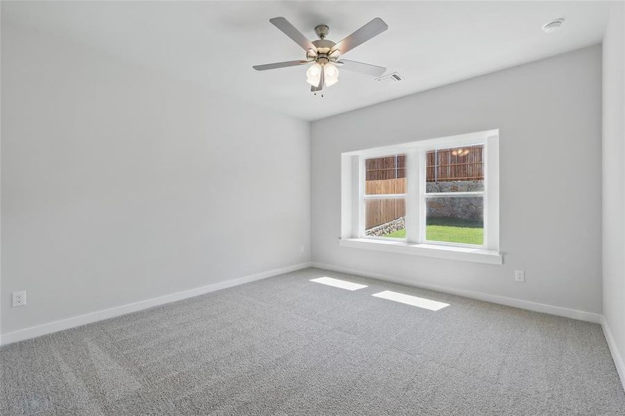 Carpeted empty room with a ceiling fan and baseboards