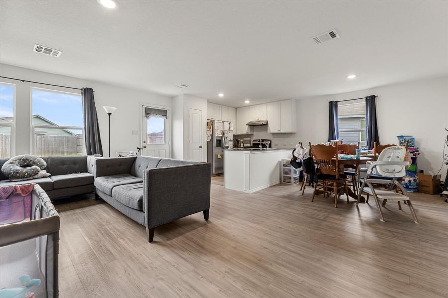 An open floor plan seamlessly connects the living area, kitchen, and dining space, all illuminated by recessed lighting.