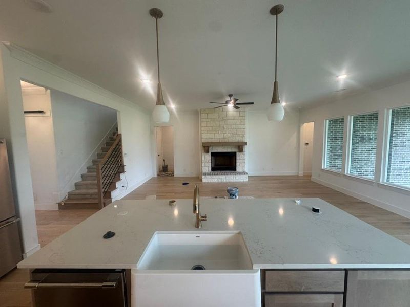 Kitchen island featuring a white farmhouse sink, gold-finish faucet, and pendant lighting