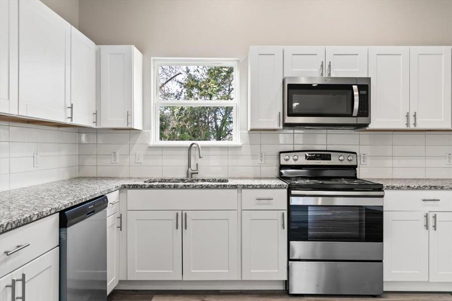 Kitchen with white cabinetry, sink, and appliances with stainless steel finishes