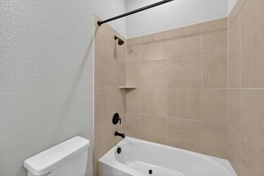 White bathtub with a built-in shelf, large-format beige wall tiles, and matte black fixtures White bathtub with a built-in shelf, large-format beige wall tiles, and matte black fixtures