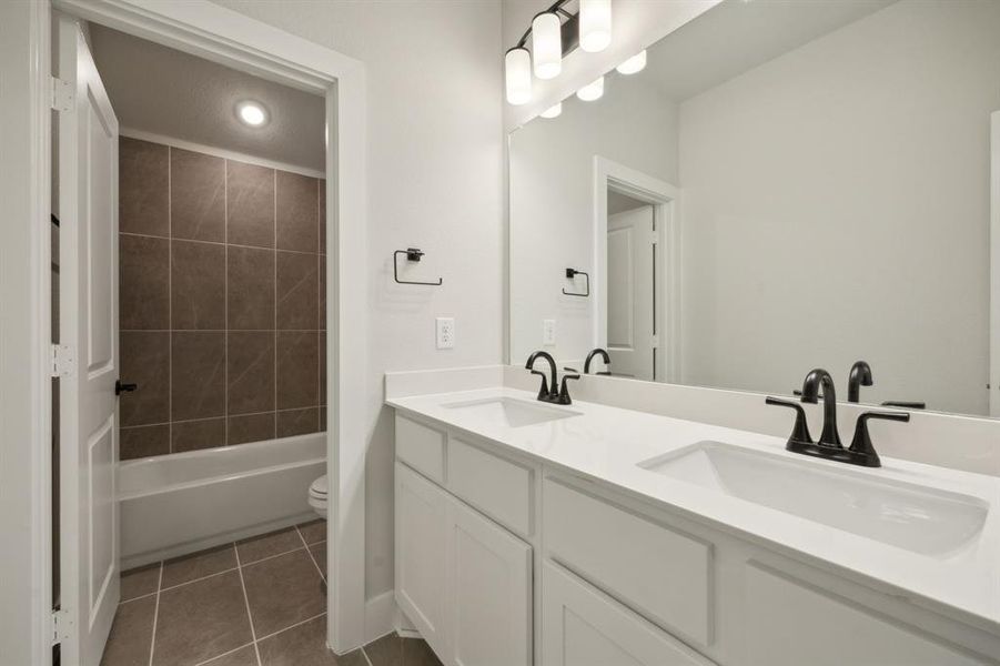 Full bathroom with tile patterned floors, tiled shower / bath, vanity, and toilet