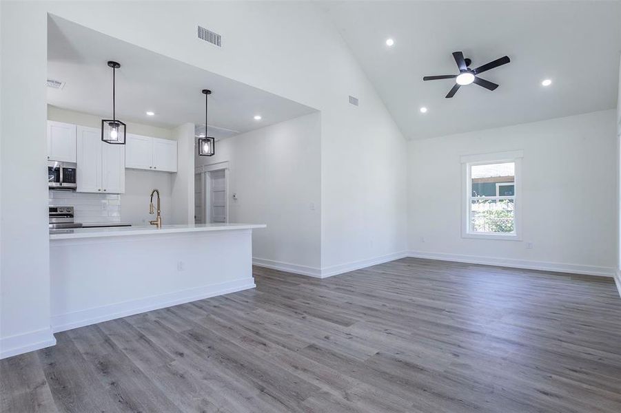 Open-concept living space featuring wood-finish flooring, a vaulted ceiling, and recessed lighting