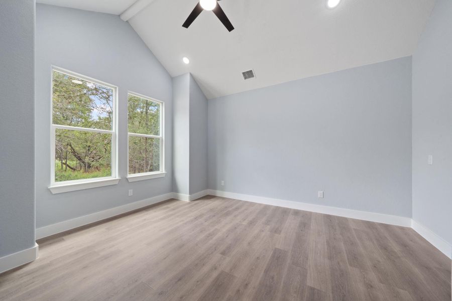 Vaulted ceiling room featuring wood-finish flooring, dual windows, a ceiling fan, and recessed lighting
