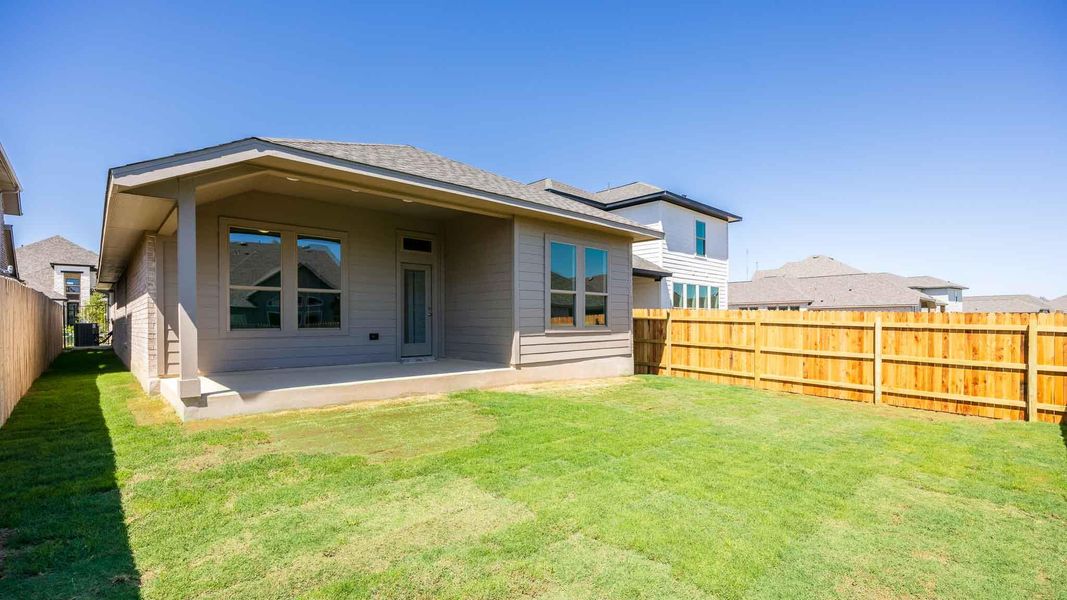 Back of house featuring a fenced backyard, a patio, and a lawn