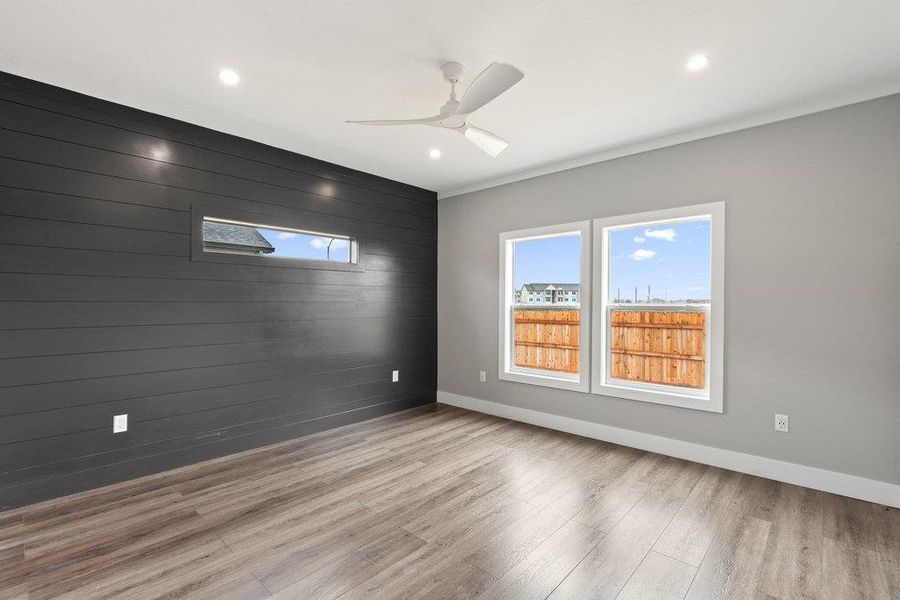 Unfurnished room with wooden walls, an accent wall, light wood finished floors, a ceiling fan, and recessed lighting