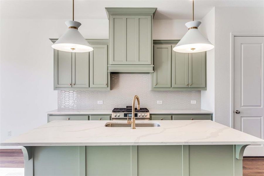 Kitchen with light stone countertops, wood-type flooring, decorative light fixtures, and sink