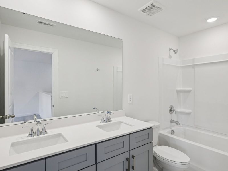 The secondary bathroom features a dual-sink vanity and oversized shower tub. The secondary bathroom features a dual-sink vanity and oversized shower tub.