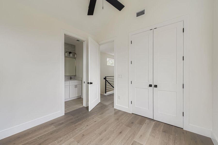 Unfurnished bedroom with light wood-type flooring, a closet, connected bathroom, and a ceiling fan Unfurnished bedroom with light wood-type flooring, a closet, connected bathroom, and a ceiling fan