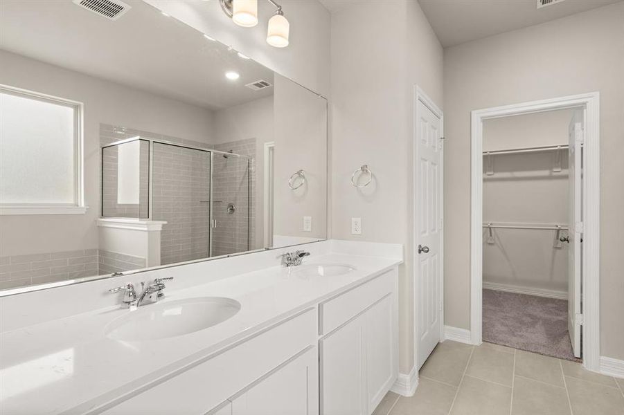 The en-suite bathroom offers a spa-like atmosphere with its elegant design, high end finishes, and tasteful lighting, creating a retreat within your own home.