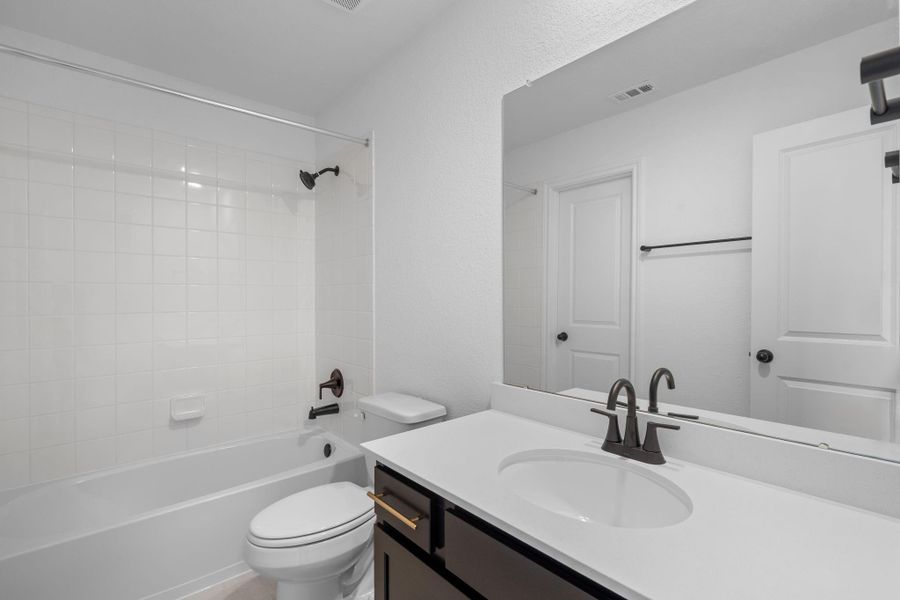 The secondary bath features tile flooring, white cabinetry and light countertops and a shower/tub combo. Perfect for accommodating any visiting family and friends.