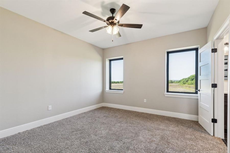 Carpeted primary bedroom featuring baseboards and a ceiling fan. Carpeted primary bedroom featuring baseboards and a ceiling fan.