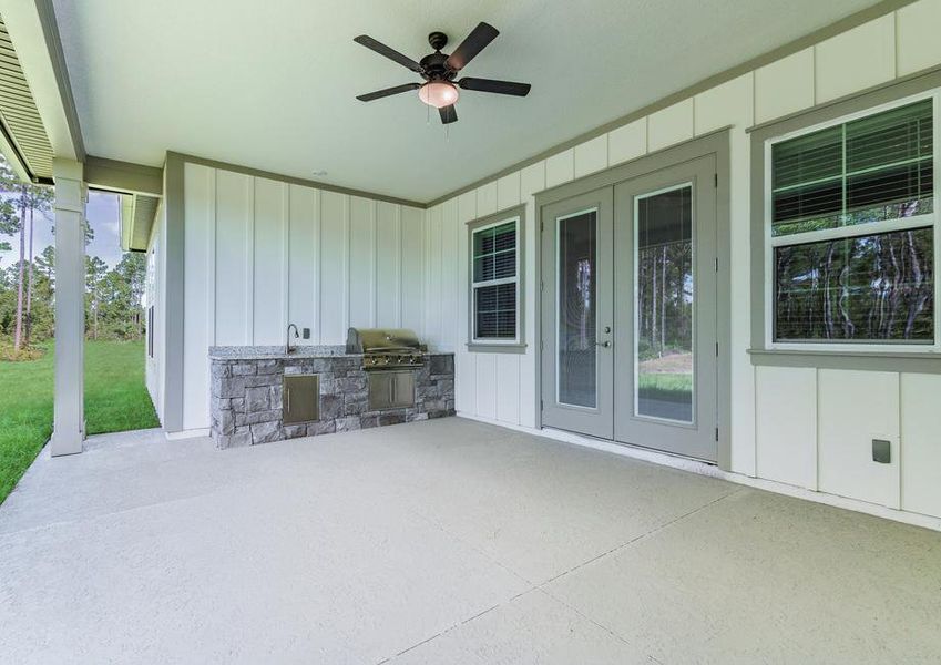 Covered outdoor kitchen with a built-in grill, sink and ceiling fan.