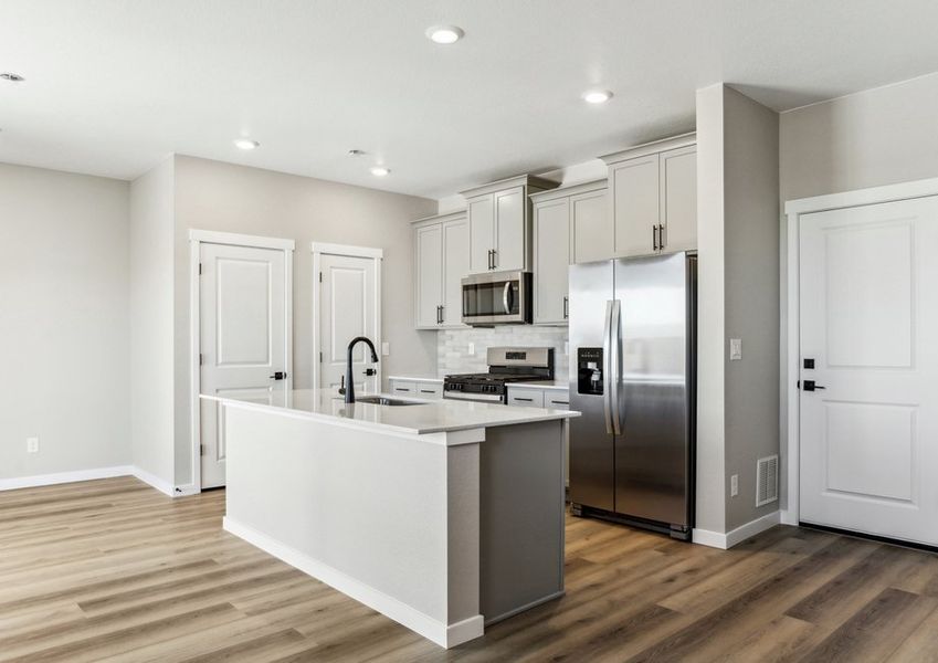 The kitchen has stainless steel appliances and plank flooring.