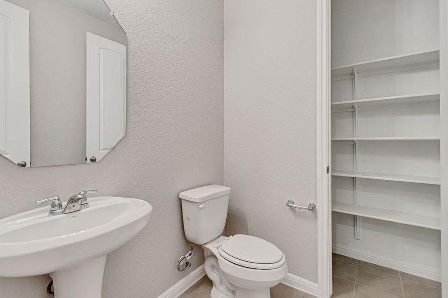 Half bathroom featuring a textured wall and light tile patterned flooring Half bathroom featuring a textured wall and light tile patterned flooring