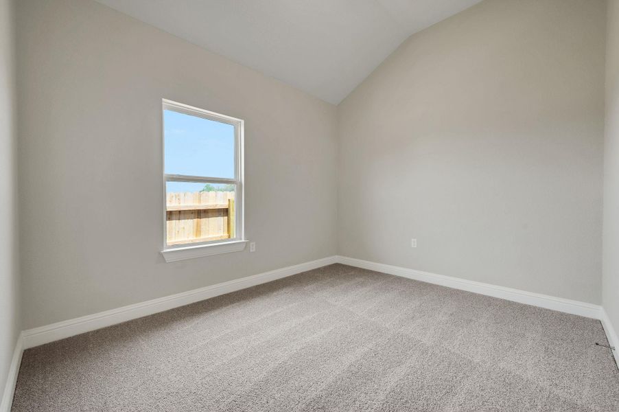 Spare room featuring carpet flooring and lofted ceiling Spare room featuring carpet flooring and lofted ceiling