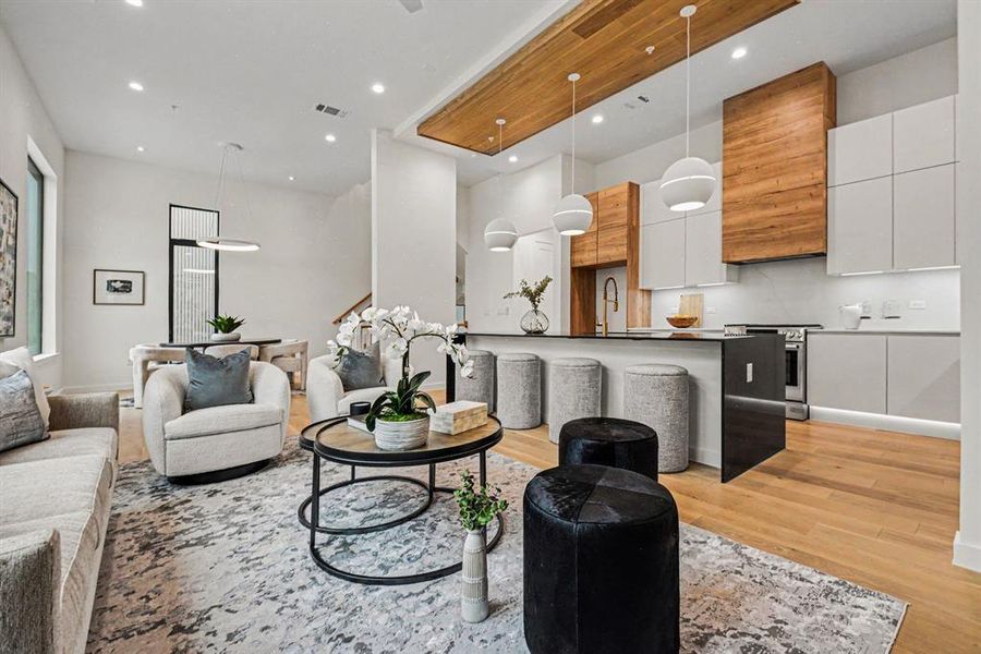 A waterfall-edge dark quartz island with bar seating, oversized globe pendants, and the circular light fixture over the dining table add to the scale and design of this gorgeous space.