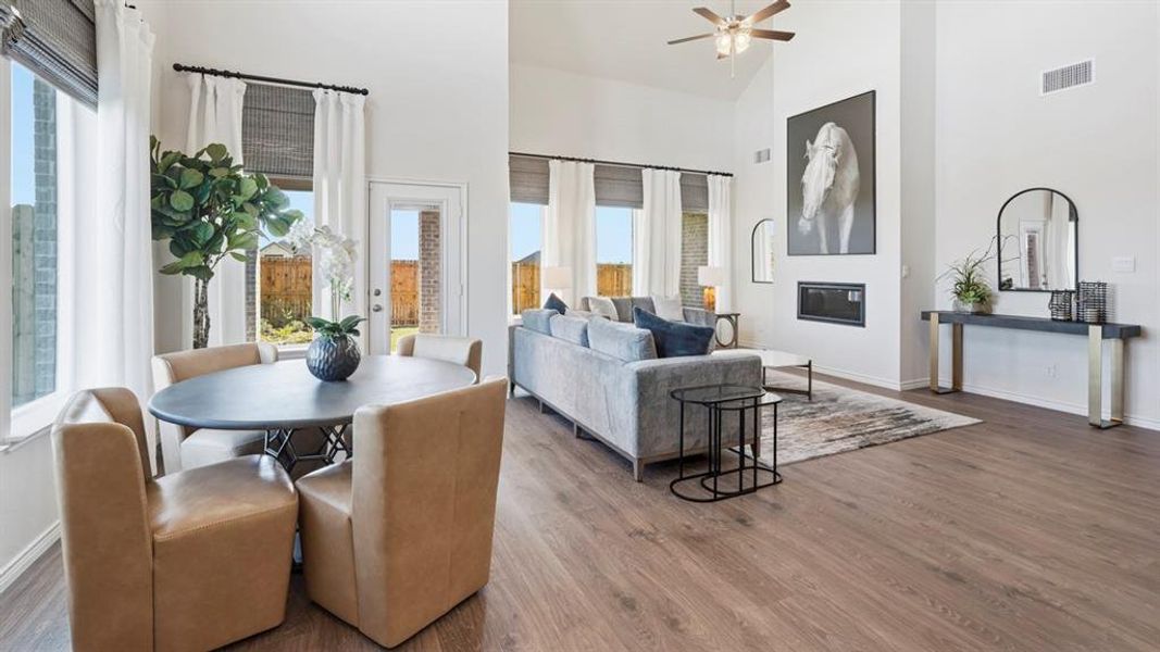 Open-concept living space featuring wood-finish flooring, vaulted ceilings, and a built-in fireplace Open-concept living space featuring wood-finish flooring, vaulted ceilings, and a built-in fireplace