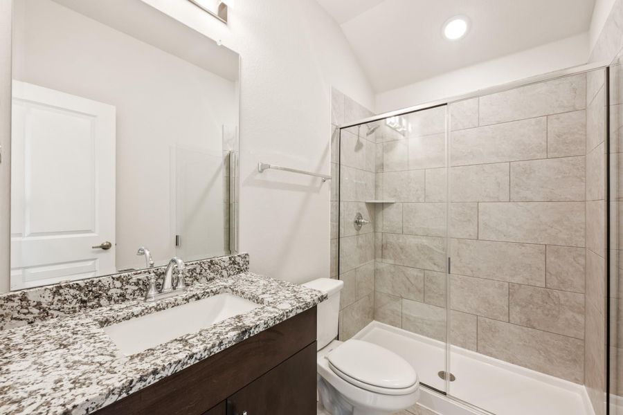 Bathroom with granite vanity, dark wood cabinets, and glass-enclosed tile shower stall Bathroom with granite vanity, dark wood cabinets, and glass-enclosed tile shower stall