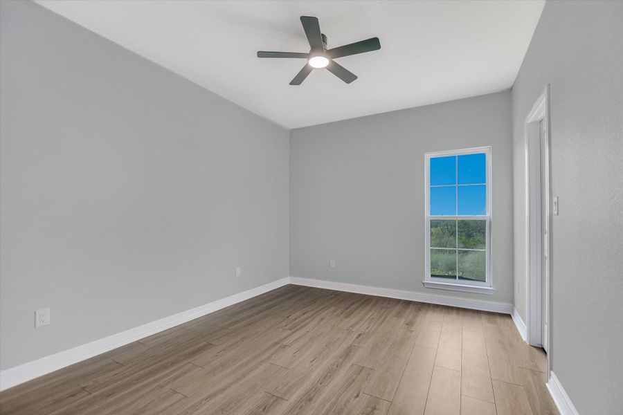 Spare room with light wood finished floors and a ceiling fan