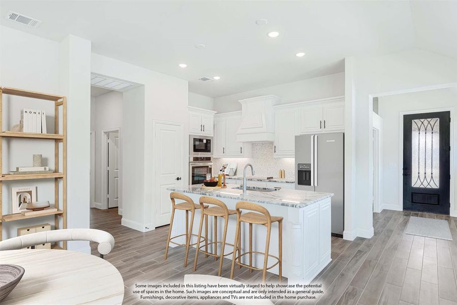 Open kitchen with white cabinets, marble island with bar stools, stainless appliances, and wood-look tile floors
