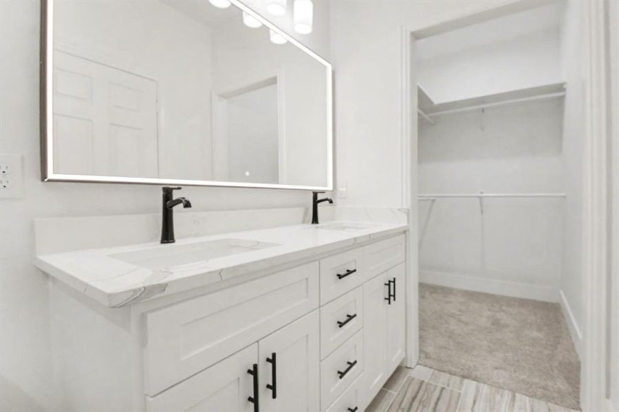 Bathroom featuring a dual sink vanity with white cabinetry, a light-colored countertop, and matte black fixtures