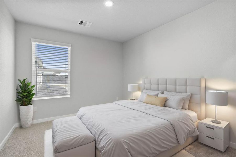 Secondary bedroom features plush carpet, custom paint, lighting, ample closet space, and a large window with privacy blinds.