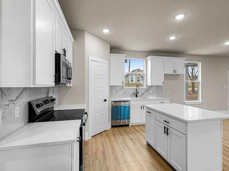 Kitchen featuring appliances with stainless steel finishes, white cabinets, light wood-type flooring, decorative backsplash, and recessed lighting Kitchen featuring appliances with stainless steel finishes, white cabinets, light wood-type flooring, decorative backsplash, and recessed lighting