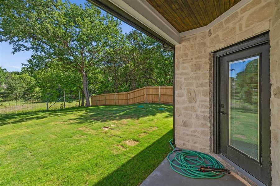 Covered patio featuring a wood-plank ceiling and stone exterior wall