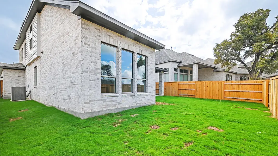 Rear view of house with a fenced backyard and brick siding
