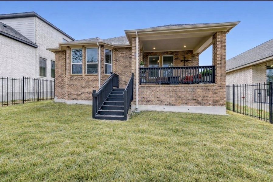 Rear view of property with a fenced backyard, brick siding, and a patio area